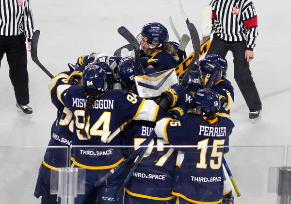 The UBC women's hockey team celebrates in a dog pile after winning.
