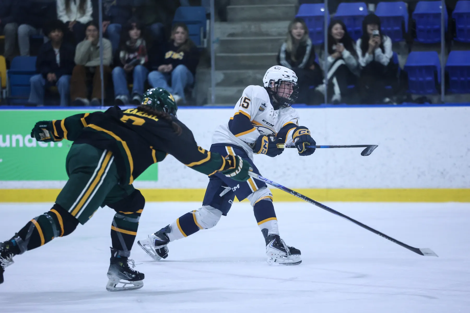 Pursued by an Alberta player in black and green, a UBC player in white and blue takes a shot