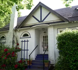 A tan house surrounded by green hedges.