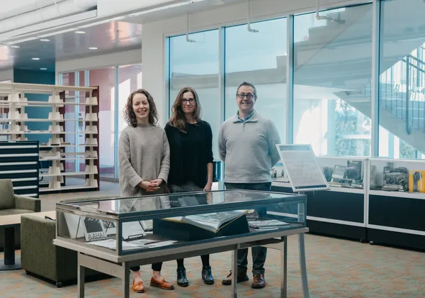 The curators of Rise Up! stand above the display cases that make up the exhibition in the MAA Library at UBC
