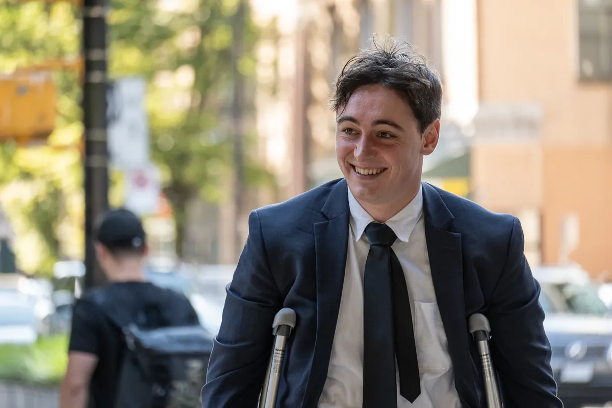 A man in a suit walks with crutches.