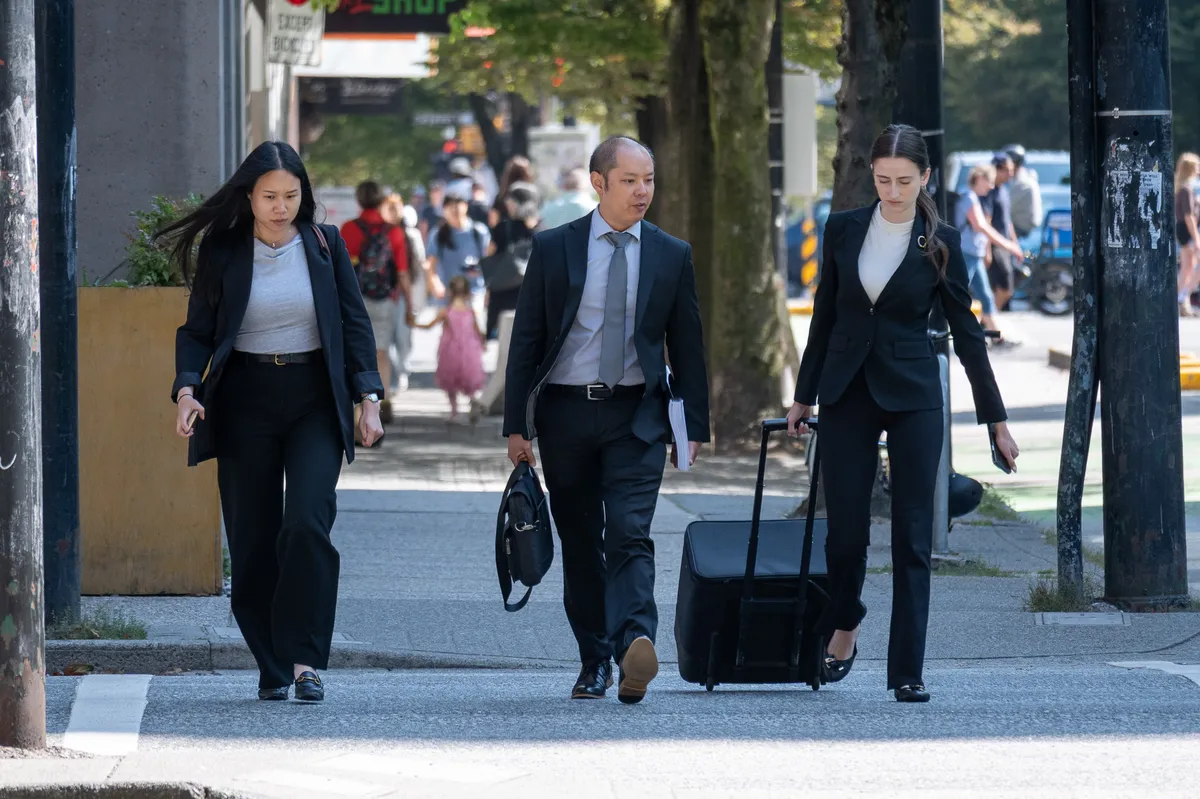 Three people walk down a sidewalk.