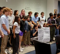 AMS Council poses for a photo. GSS Councillor Katelynn Hubenig and AMS President Dylan Evans hold a large paper displaying the text of a motion.