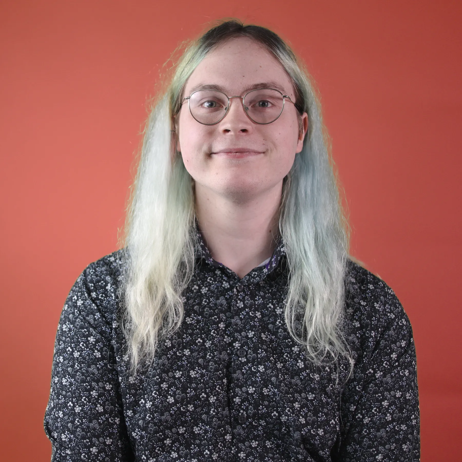 A person smiles in front of a red background.