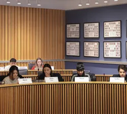 Four people sit at a rounded wooden table.
