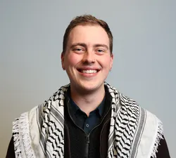 Photo of a man in a black shirt and with a grey background.