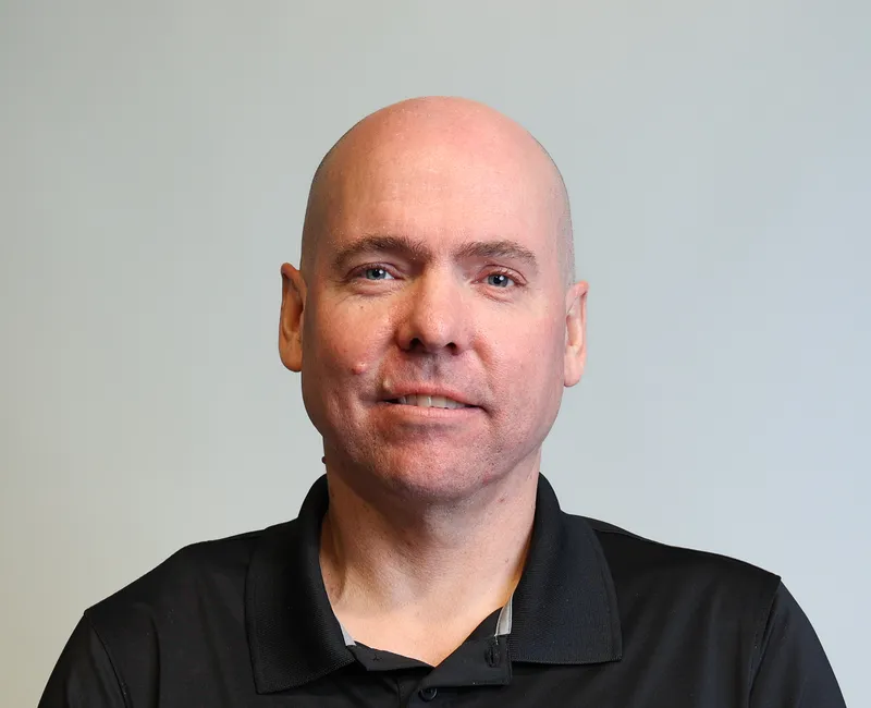 Photo of a man in a black shirt facing the camera with a blank whiteground.