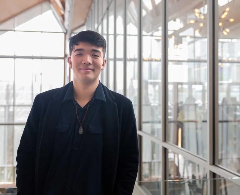 A person faces the camera in a large, light-filled atrium.