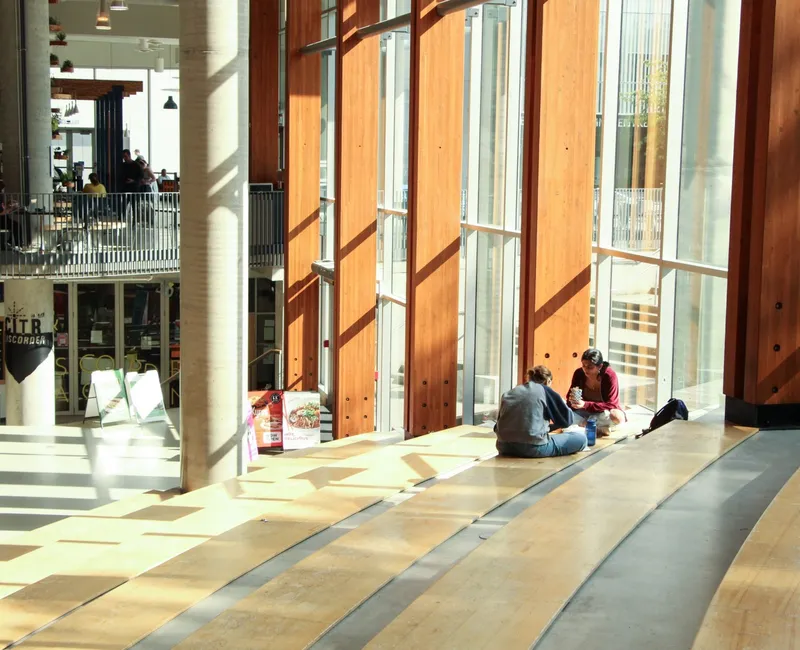 Inside the AMS Nest, students sit on steps as sunlight streams in.