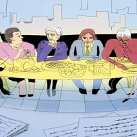 Group of people in office sitting around a long table eating a meal. In the foreground, pen and paper are laid on a table.