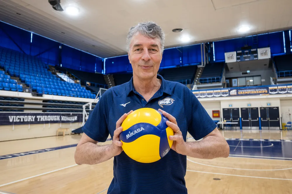 Reimer holds a volleyball in both hands at centre court in War Memorial.