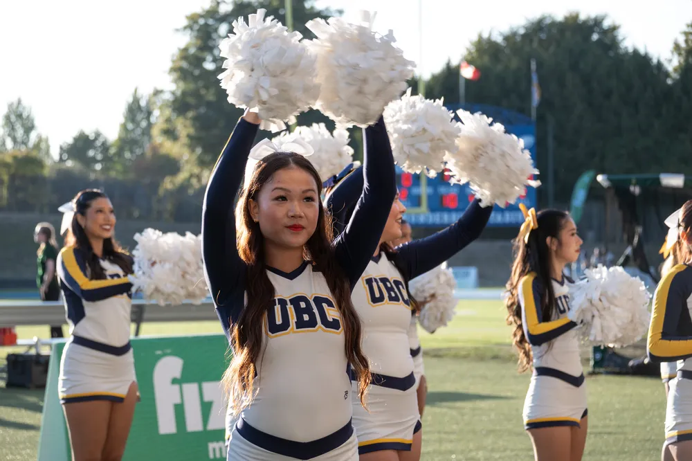 The UBC Cheer Team cheers from the sidelines during the game.