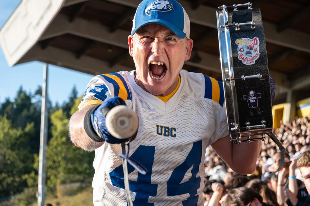 Super-fan Crazy P points his mallet at the camera after banging his drum, yelling out cheers and hyping up fans in the stands.