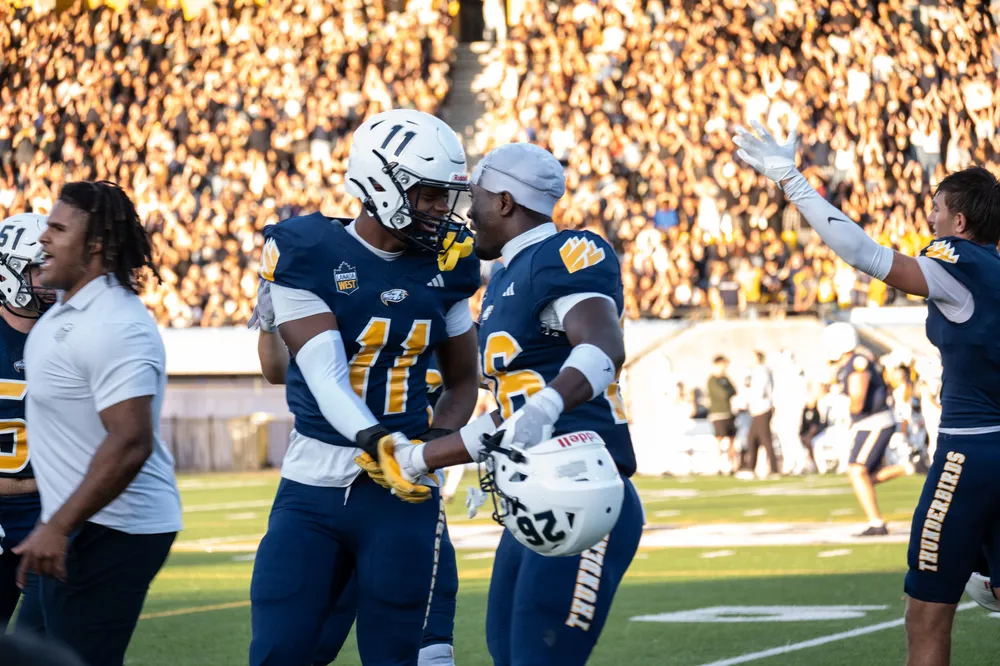 Xander Prosper (#11) and Derek Durand (#26) celebrate after the Thunderbirds take the lead, bringing the score to 10-7.