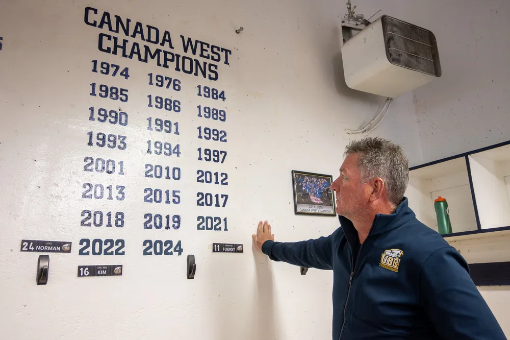 Mike Mosher looks up at the wall in the T-Birds locker room that displays their Canada West titles.