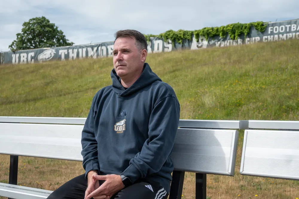 Symons sits on a bench on the sideline of Thunderbird Stadium.