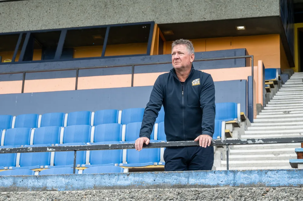 Mike Mosher stands in the bleachers at Thunderbird Stadium, looking out at the field.