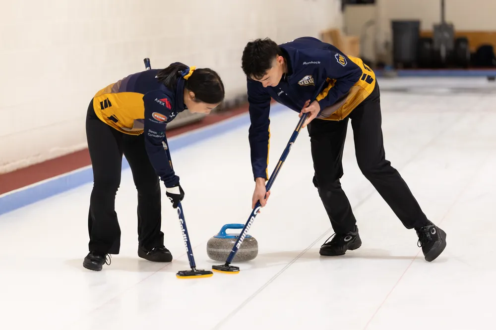Two UBC curlers sweep the rock.