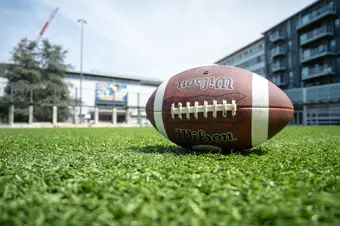 A football lying on the grass in front of War Memorial Gymnasium.