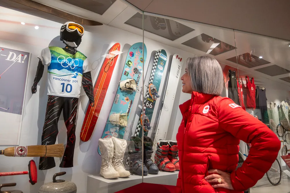 Loo looks up at a display case with snowboard equipment from the Olympics behind the glass.