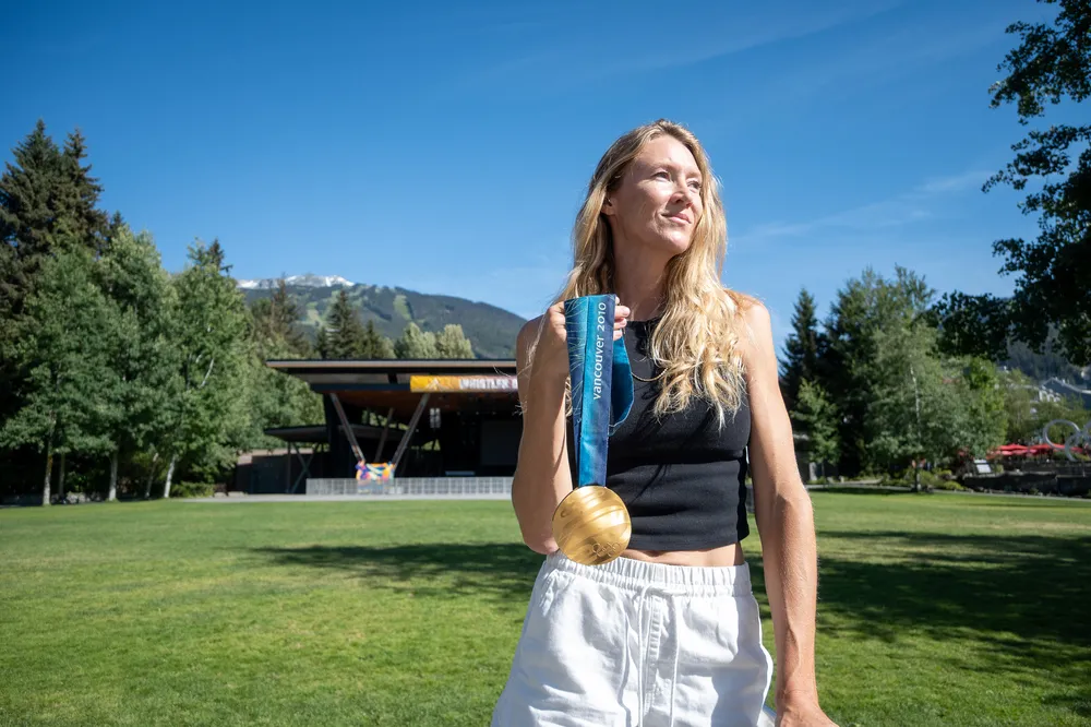 McIvor stands in an open field in Whistler, with her gold medal over her shoulder.