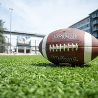 A football lying on the grass in front of War Memorial Gymnasium.
