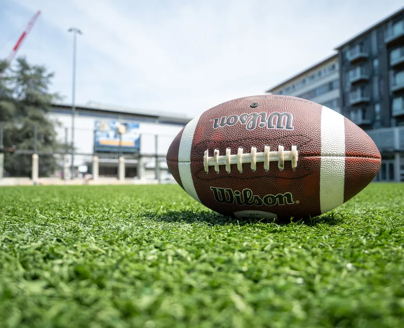 A football lying on the grass in front of War Memorial Gymnasium.