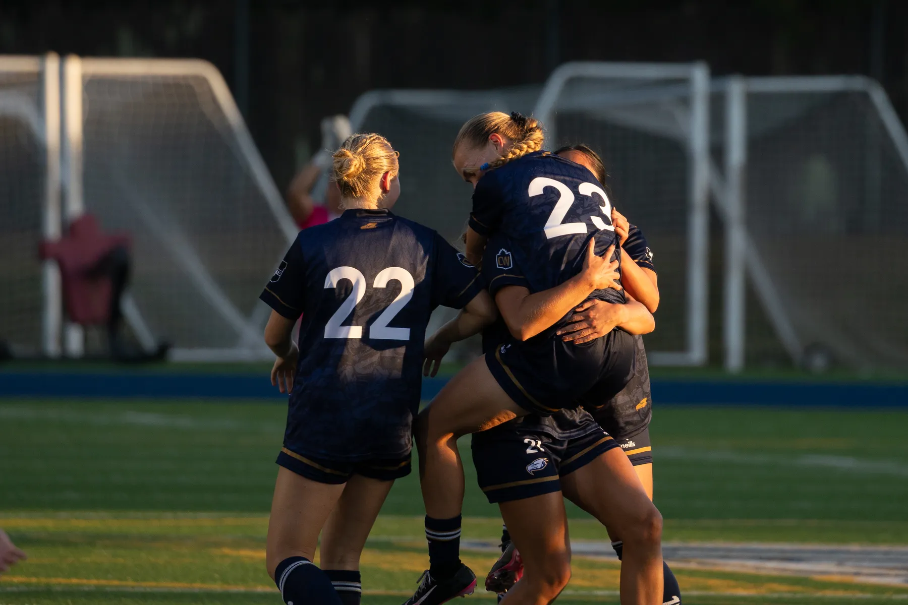 Norman jumps into the arms of her teammates, celebrating together.