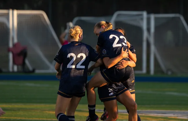 Norman jumps into the arms of her teammates, celebrating together.