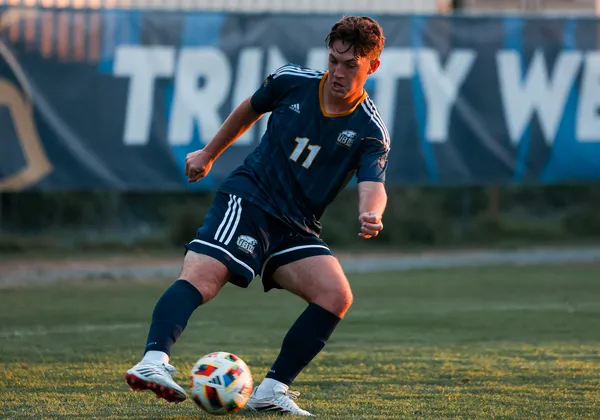 Brennen Fuerst dribbles the ball as the sun sets, wearing a blue Thunderbirds jersey