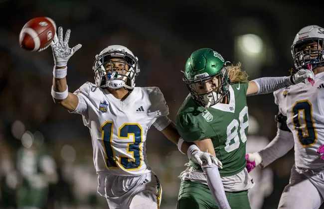 A T-Bird reaches out for a ball and barely misses it, with a Saskatchewan receiver nearby