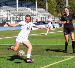 Norman, in a white T-Birds jersey, takes a shot with a defender in a brown jersey behind her.