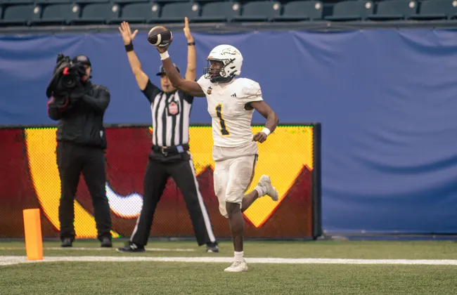 A UBC player holds the ball up in celebration.