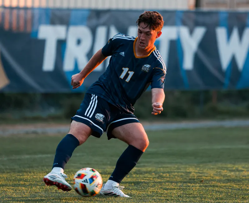 Brennen Fuerst dribbles the ball as the sun sets, wearing a blue Thunderbirds jersey