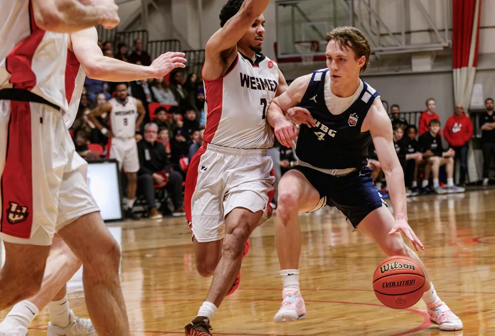 Holt Tomie dribbles his way past a Winnipeg player, with another Wesman right in front of him.