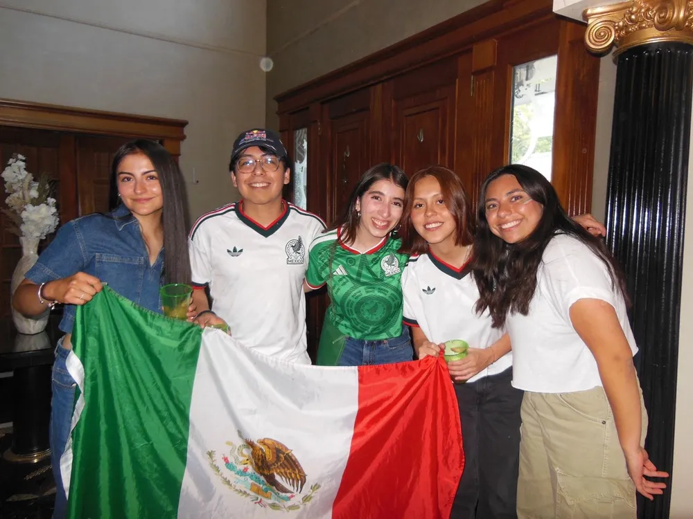 A group of students hold up a Mexican flag while celebrating the World Cip