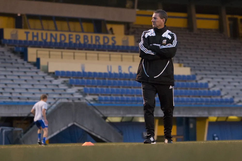 Mike Mosher, in a black UBC jacket, overlooks practice