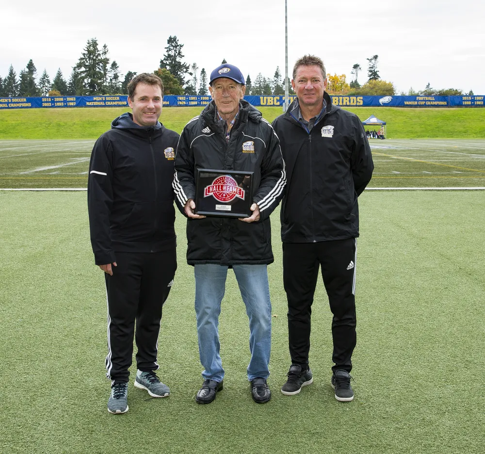 Symons stands with both Dick and Mike Mosher at Thunderbird Stadium, with Dick holding up his Hall of Fame plaque.