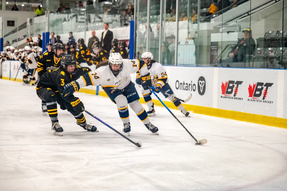 A UBC player skates with the puck past a Waterloo defender.