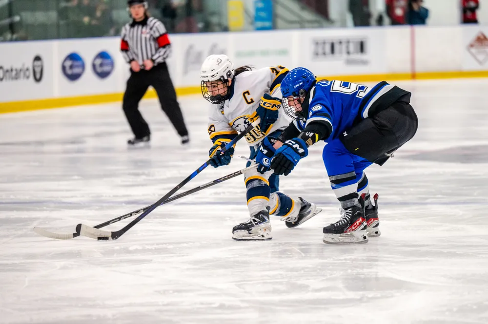 Wong, in a white jersey, gets a shot off with a Montreal defender in her face, in a blue jersey.