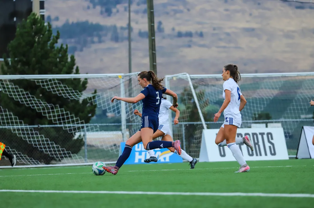 A T-Bird runs up the field as a Heat player gives chase from behind her.