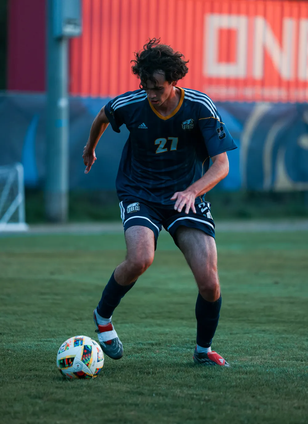 Rukavina dribbles the ball upfield as the sun sets behind him