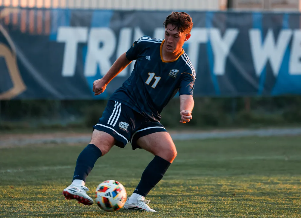 Brennen Fuerst dribbles the ball as the sun sets, wearing a blue Thunderbirds jersey