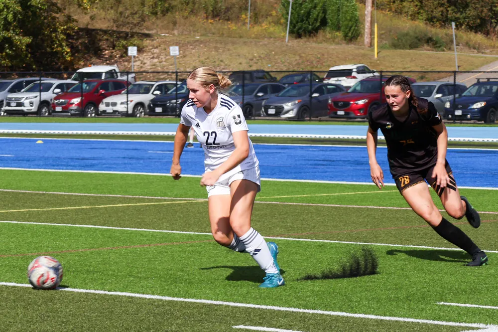 A UBC player runs up the pitch with the ball, being chased by a Timberwolves player