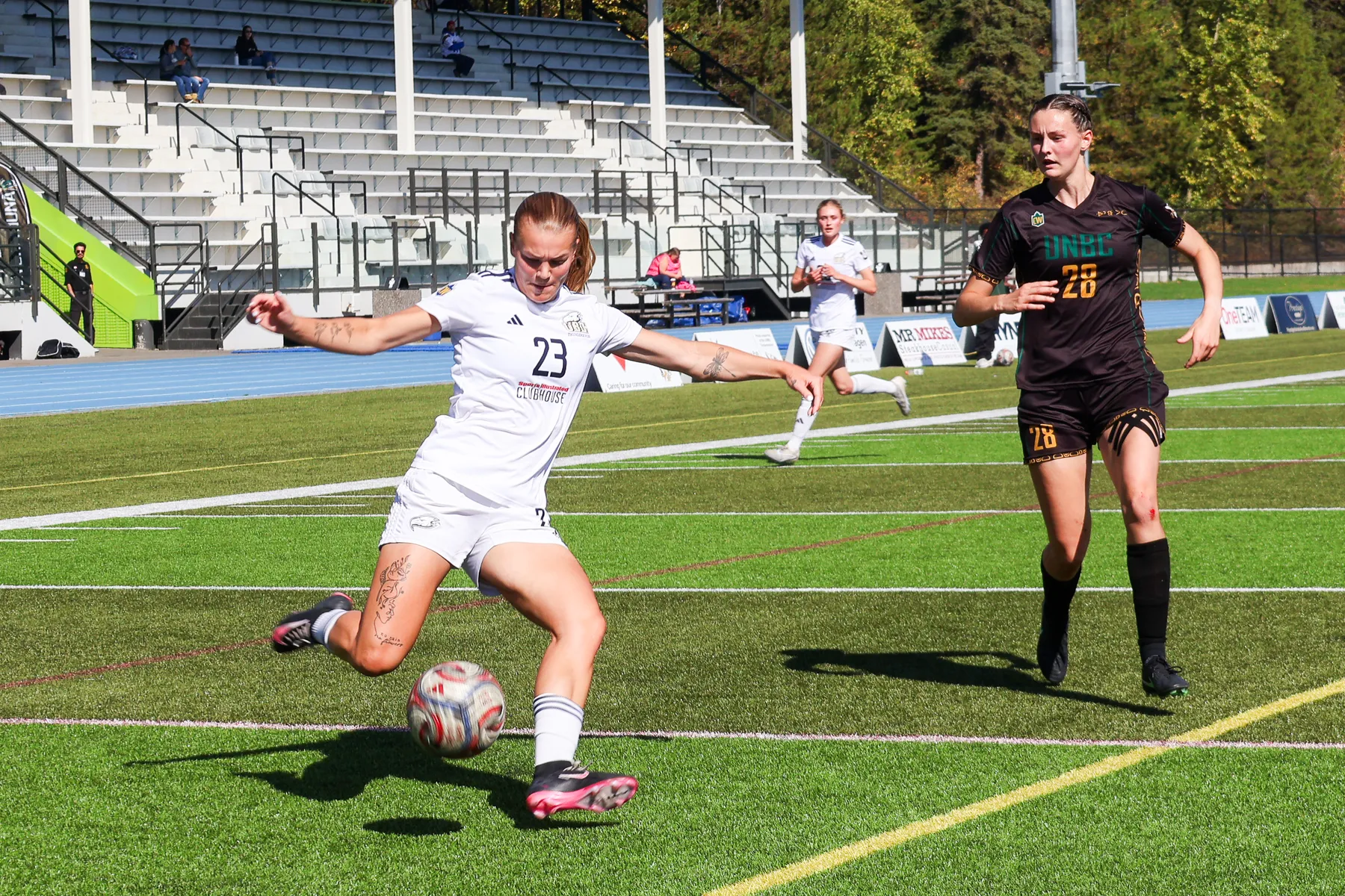 Norman, in a white T-Birds jersey, takes a shot with a defender in a brown jersey behind her.
