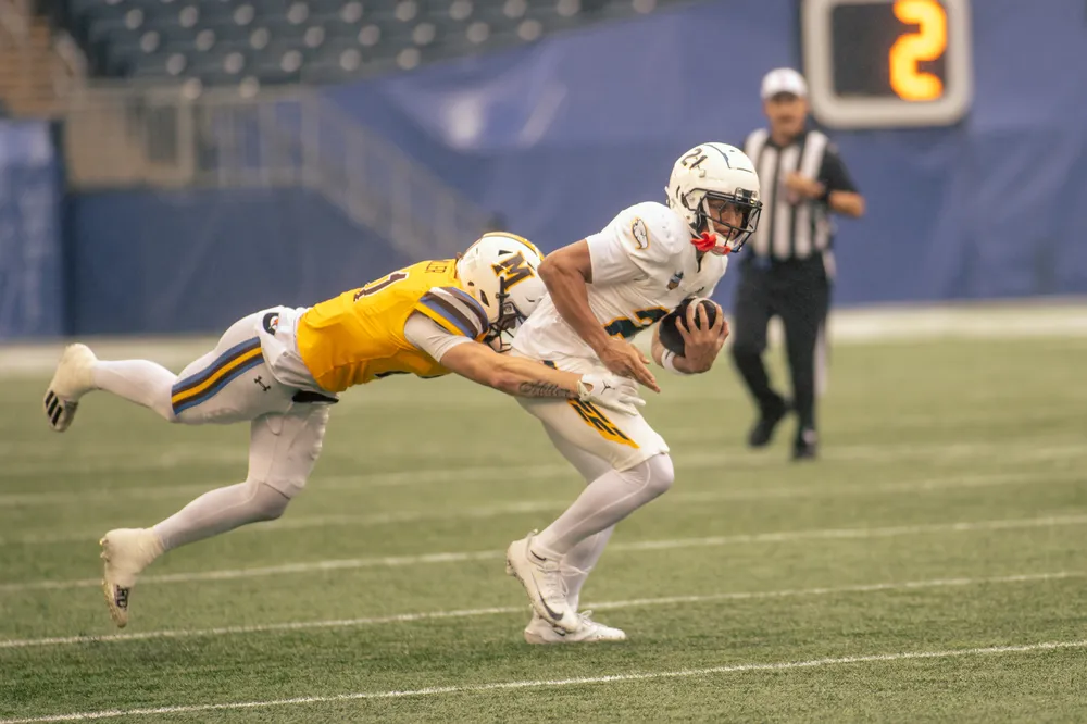 A UBC player gets tackled by a Manitoba defender