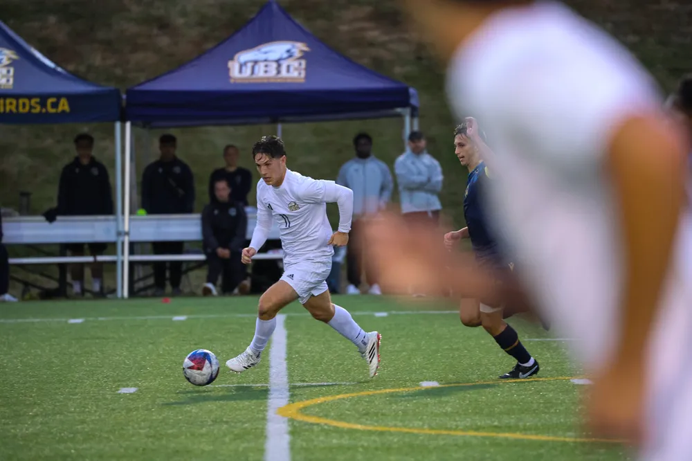 Midfielder Brennan Fuerst runs upfield with the ball as his teammates flank him.