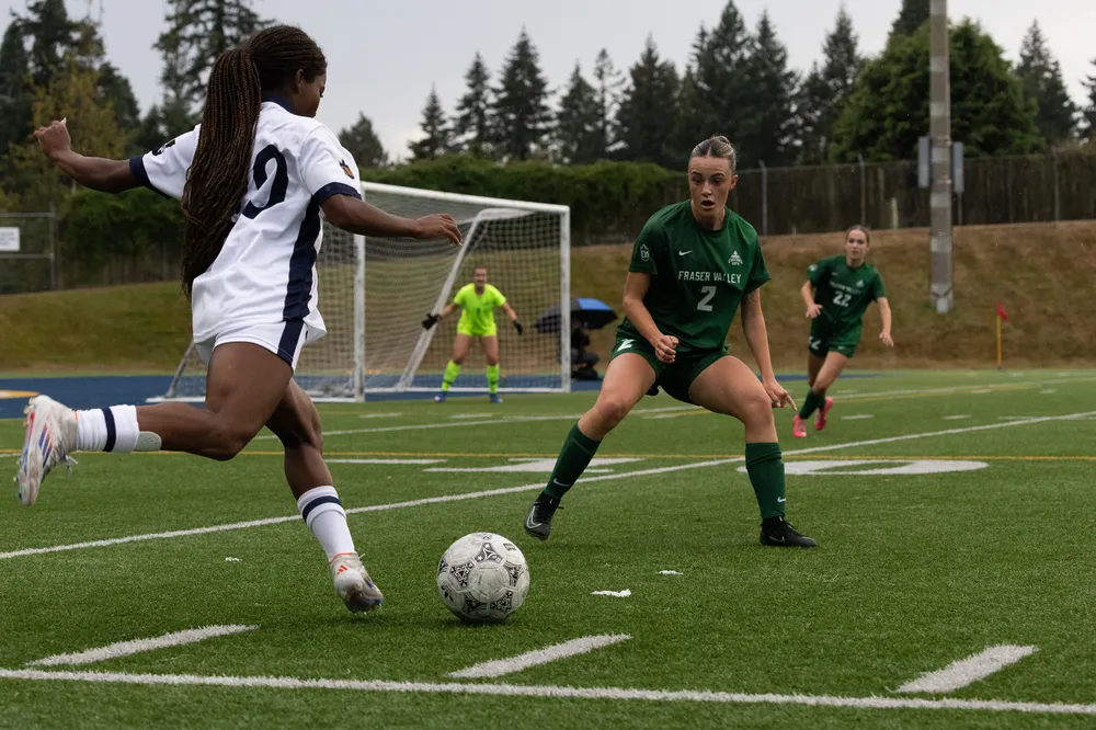 A T-Bird dribbles towards the net from the sideline, with a Cascades defender in front.