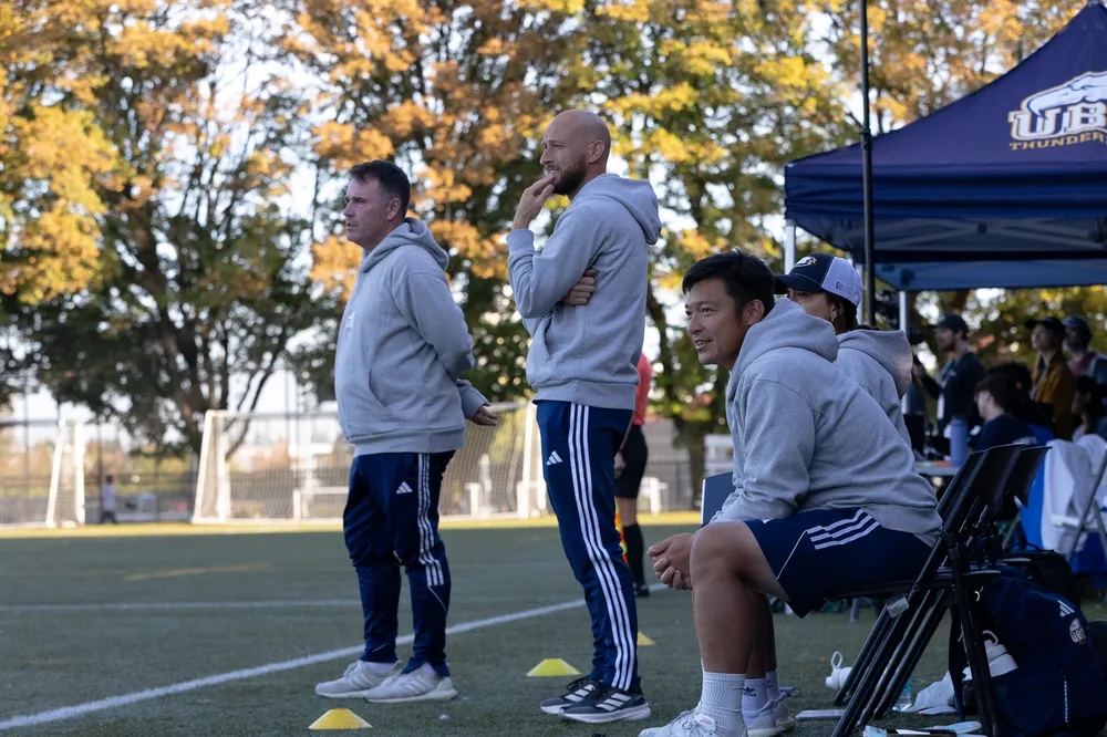The coaches stand on the sideline.