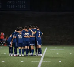 The men's soccer team huddles up on the field
